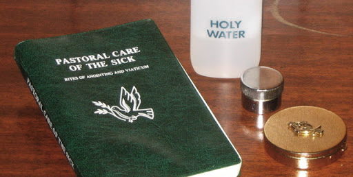 Green bible, holy water, and 2 pyx on a wooden table