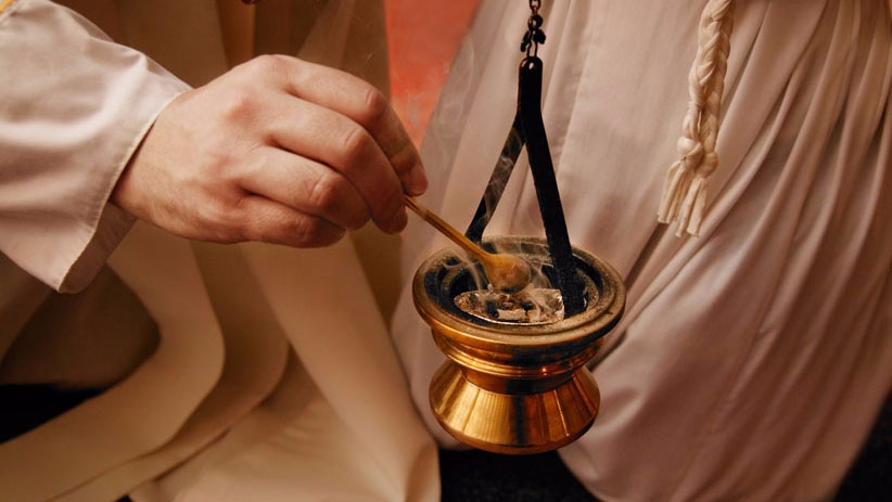 Hand putting incense into thurible
