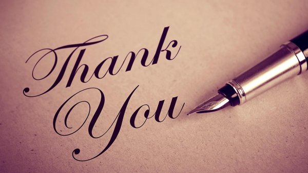 A thank you message written in cursive on parchment paper with a fountain pen laying beside it