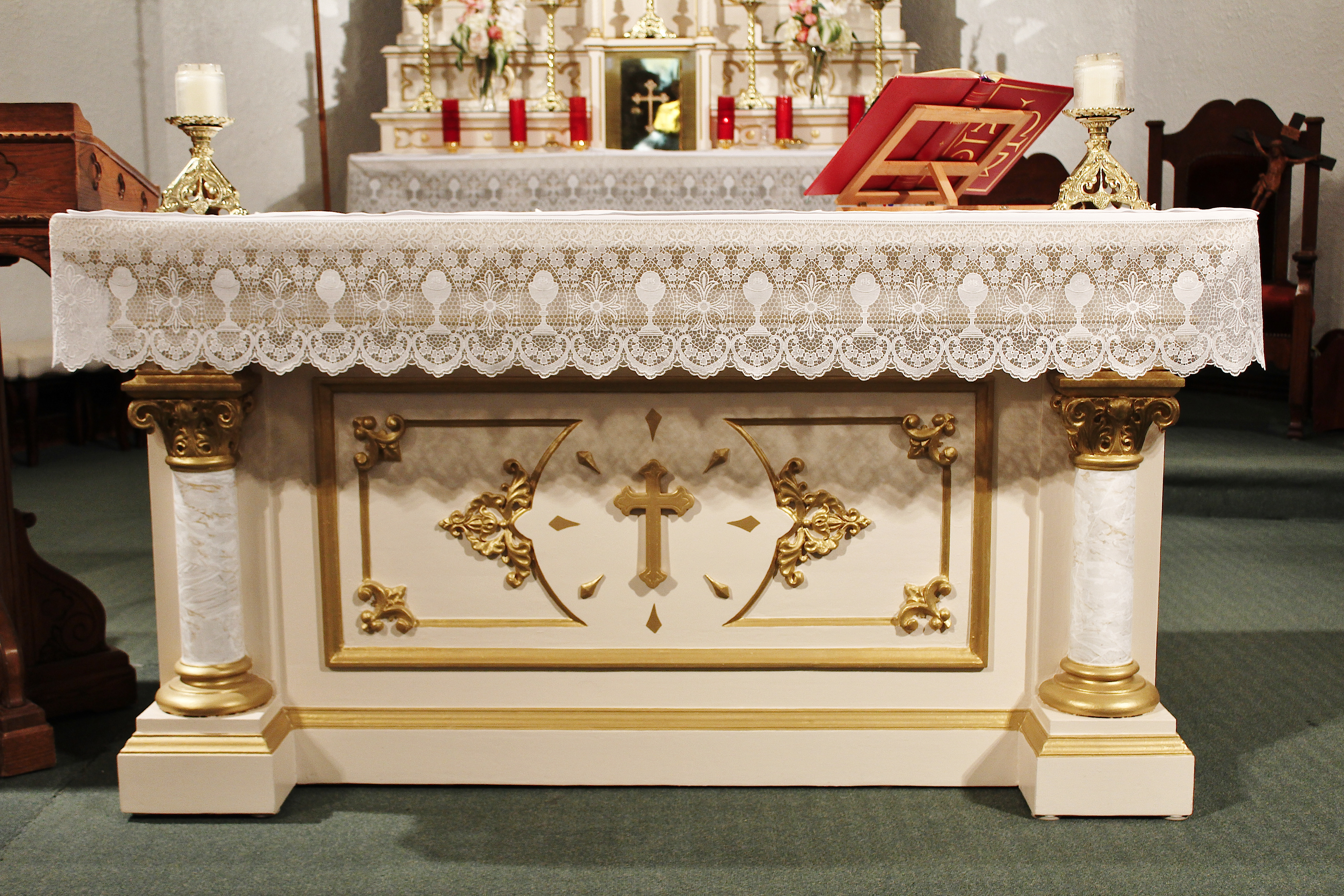 White Altar with lace cloth, ornate gold painted filigree, and marble columns