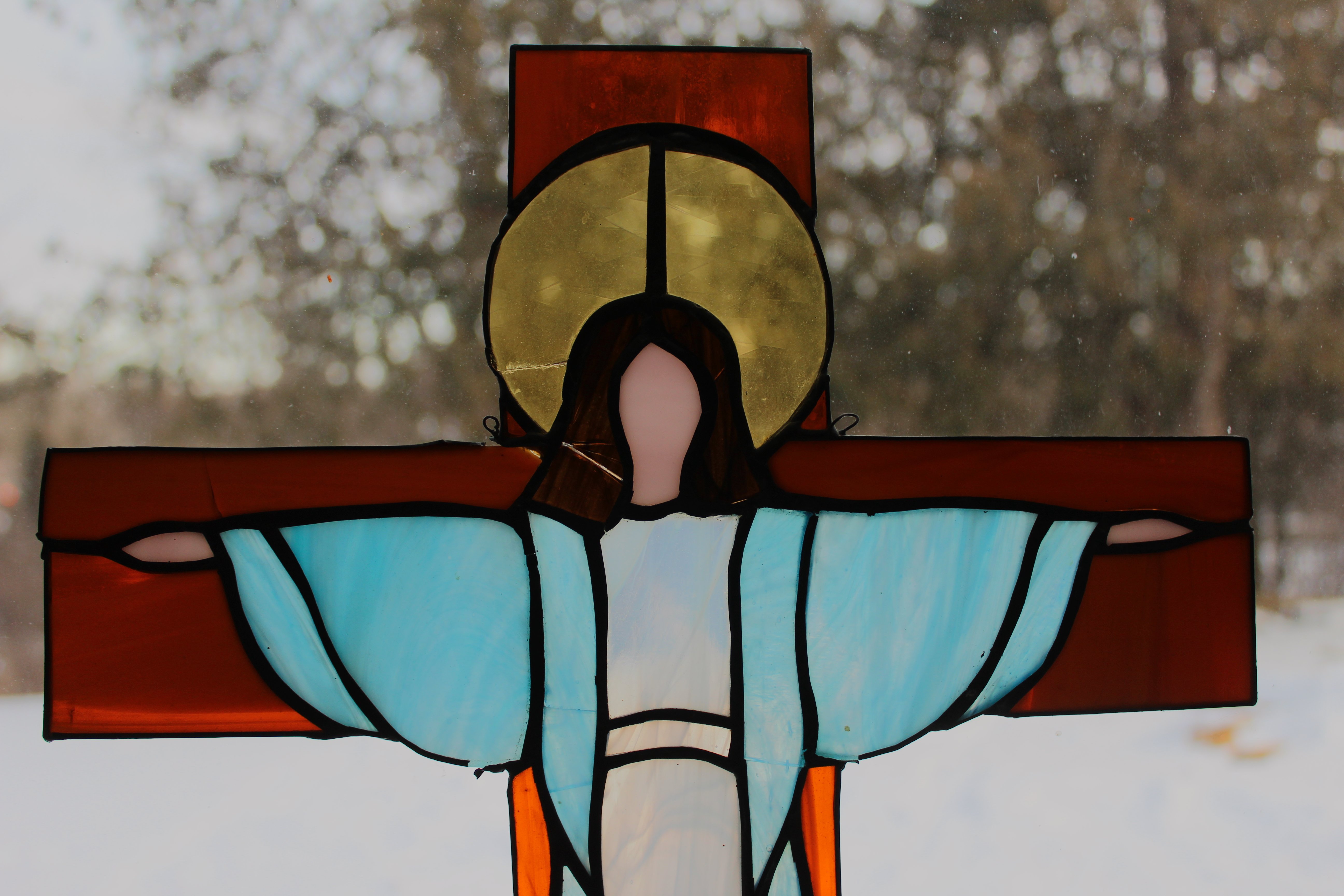 small stained glass cross with an image of a clothes body and halo