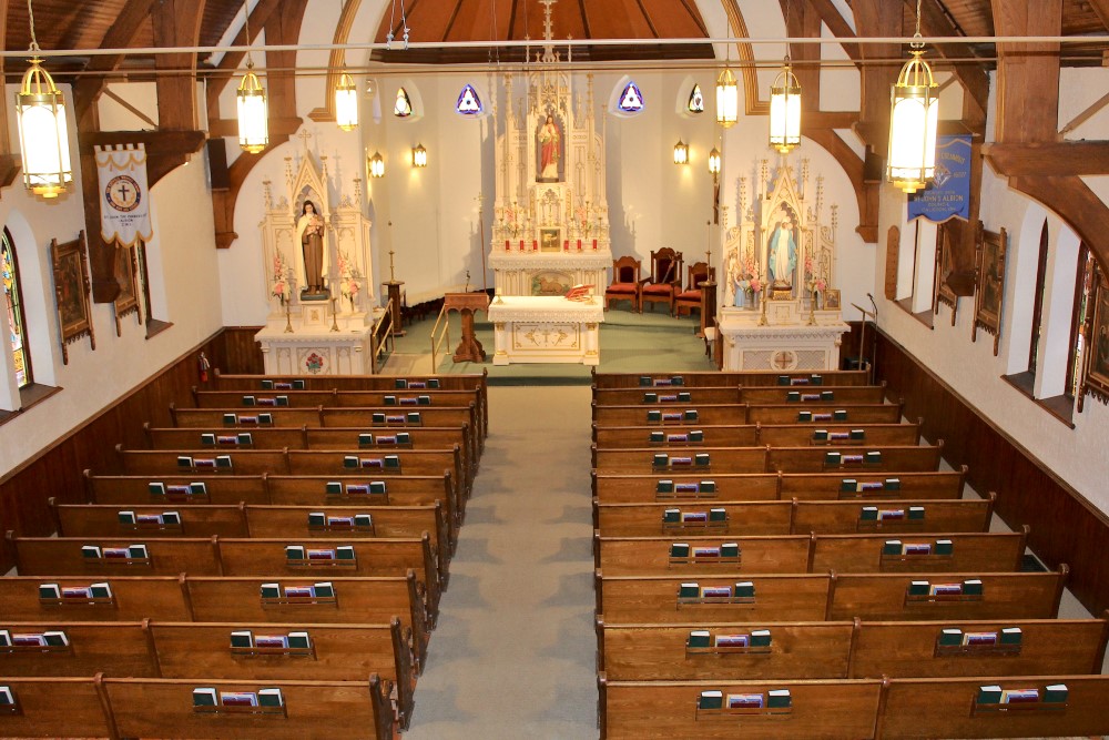 View of the body of a church, showing pews and sactuary space from the choir loft.