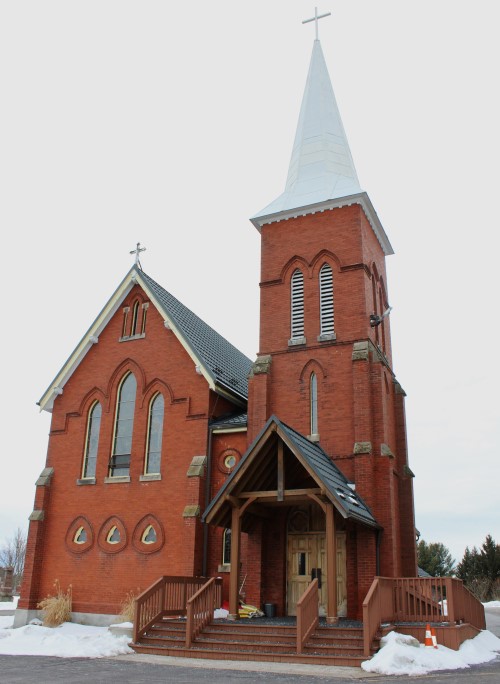 Outdoor view of St. John's Catholic Church in Caledon. A red brick building with a white steeple roof and cross